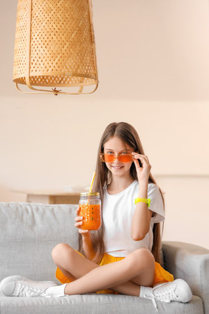 Little girl with glass jar of juice at homeの写真素材