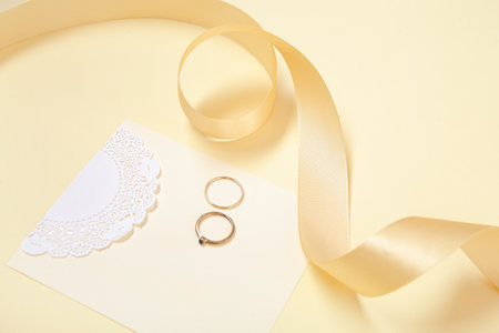 Golden ribbon, female rings and card on color background, closeupの写真素材