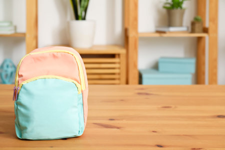 Stylish school backpack on wooden table in living room
