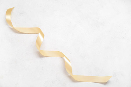 Golden satin ribbon on white grunge backgroundの写真素材