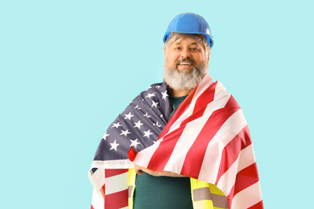 Portrait of happy senior man in hardhat with USA flag on blue background. Labor Day celebration