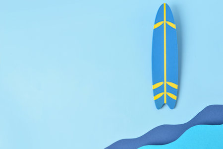 Creative composition with paper waves and mini surfboard on blue backgroundの写真素材