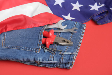 USA flag and different tools in jeans pocket on red background. Labor Day celebrationの写真素材
