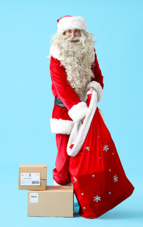 Santa Claus putting parcels into gift bag on blue backgroundの写真素材