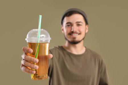 Young man with glass of juice on green background, closeupの写真素材