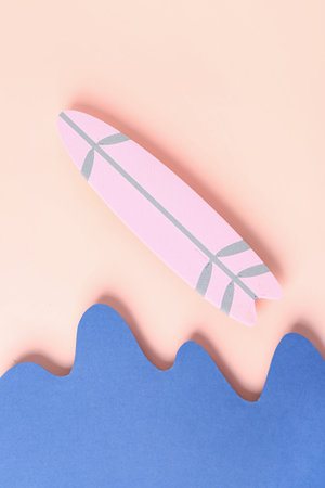 Creative composition with paper waves and mini surfboard on pink backgroundの写真素材