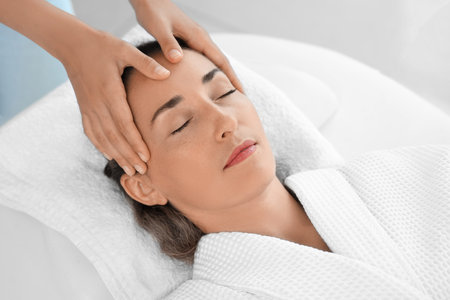 Beautiful mature woman receiving face massage in spa salonの写真素材