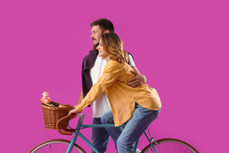 Happy couple in love with bicycle on violet backgroundの写真素材