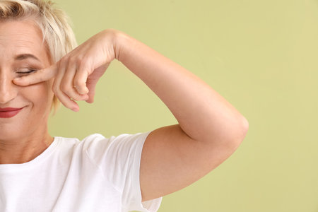 Mature woman doing face building exercise on green background, closeupの写真素材