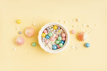 Bowl with colorful sprinkles and sweets on light yellow backgroundの写真素材