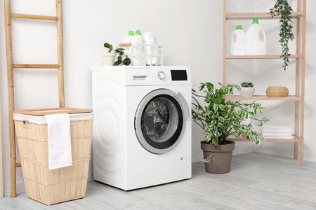 Modern washing machine with basket, shelving unit and ladder near white wall. Interior of home laundry roomの写真素材