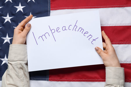 Woman holding IMPEACHMENT picket poster against USA flag backgroundの写真素材