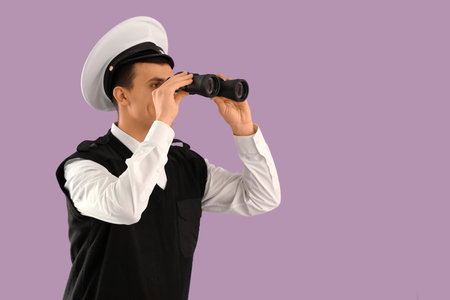 Young sailor looking through binoculars on lilac backgroundの写真素材