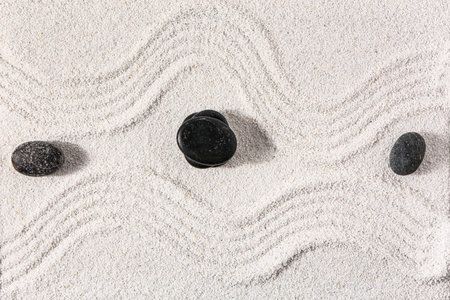 Stones on sand with lines in Japanese rock garden, top view. Zen concept
