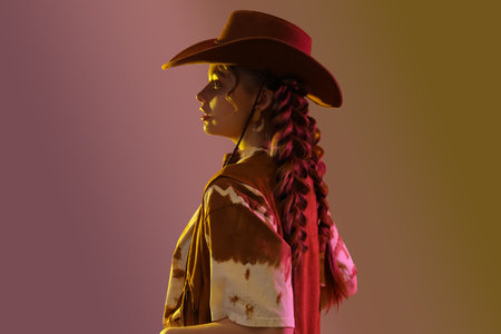Beautiful young woman with braids and cowboy hat on light backgroundの写真素材