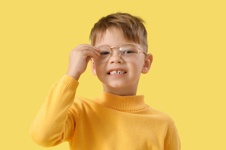 Cute little boy in eyeglasses on yellow background, closeupの写真素材