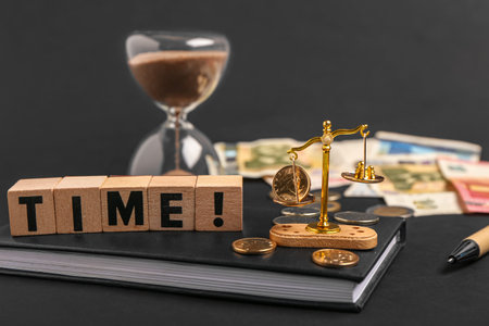 Cubes with word TIME and mini scales with coins on black background. Time management concept