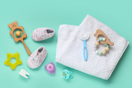 Towel with children's toothbrush, shoes and toys on turquoise background