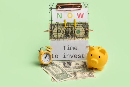Composition with text TIME TO INVEST, piggy bank and money on green background. Time management conceptの写真素材