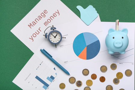 Paper with text MANAGE YOUR MONEY, piggy bank and alarm clock on green background. Top view