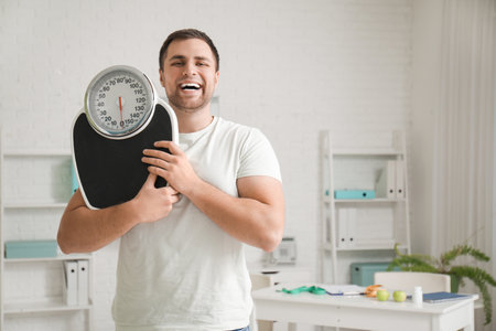 Young man with weight scales at nutritionist's officeの写真素材