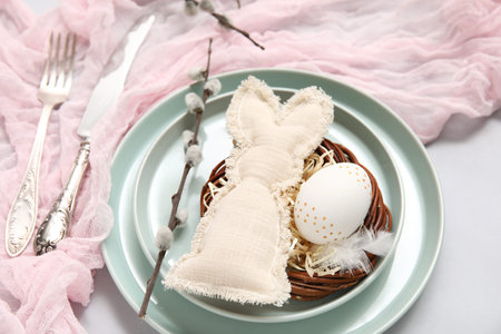 Stylish festive table setting for Easter celebration with nest on white background