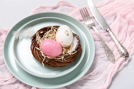 Stylish festive table setting for Easter celebration with nest on white background