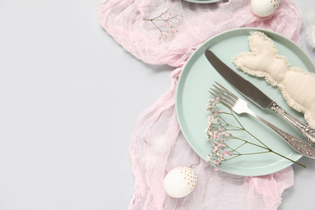 Stylish festive table setting for Easter celebration with toy rabbit on white backgroundの写真素材