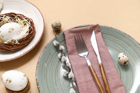 Stylish festive table setting for Easter celebration with nest on beige background