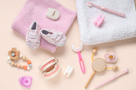 Towels with children's toothbrushes, shoes and toys on beige background
