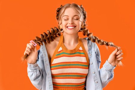 Happy smiling young woman with braids on orange background
