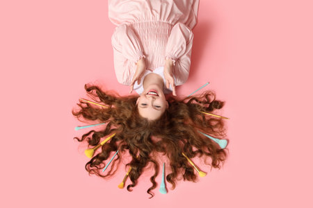 Beautiful young woman with makeup brushes on pink backgroundの写真素材