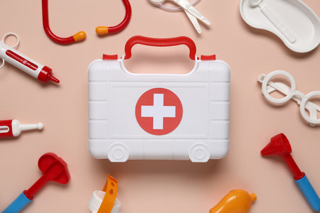 Toy first aid kit with stethoscope, reflex hammer and glasses on beige background. Top viewの写真素材