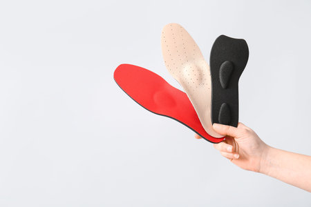 Female hands holding orthopedic insoles isolated on white backgroundの写真素材