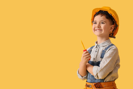 Cute little builder with toy screwdriver on yellow backgroundの写真素材