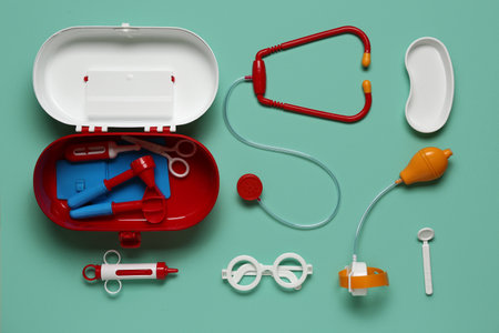 Toy first aid kit with stethoscope, injection and glasses on turquoise background. Top viewの写真素材