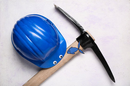 Hardhat, pick and decor on light background. April Fool's Day celebrationの写真素材