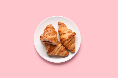 Plate with tasty croissants on pink backgroundの写真素材