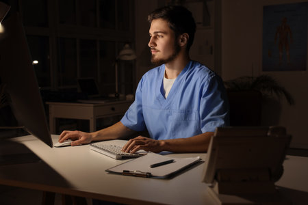Male nurse with computer working evening shift in clinicの写真素材