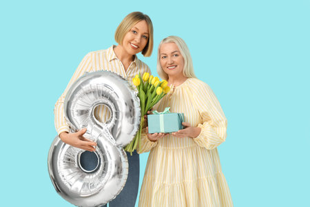 Adult woman with her smiling mother, bouquet of tulips and balloon in shape of figure 8 on blue...