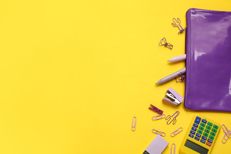 Purple pencil case and different stationery on yellow backgroundの写真素材