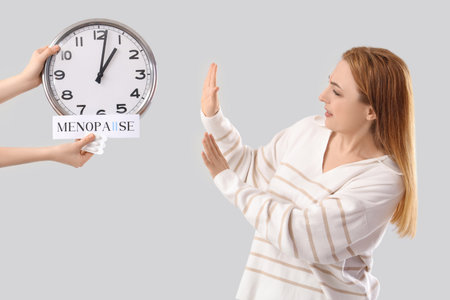 Mature woman rejecting clock and suppositories on light background. Menopause conceptの写真素材