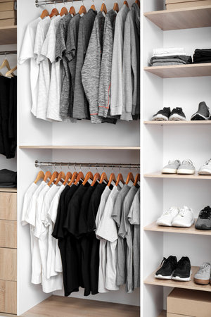 Rack with stylish T-shirts and sneakers in modern man's wardrobeの写真素材