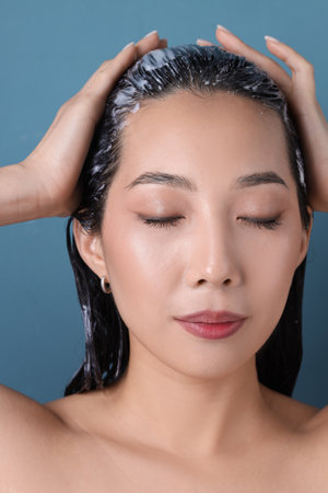 Beautiful Asian woman with hair mask on blue background, closeupの写真素材