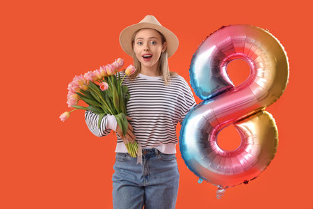 Young woman with hearing aid holding tulips and balloon in shape of figure 8 on orange background....