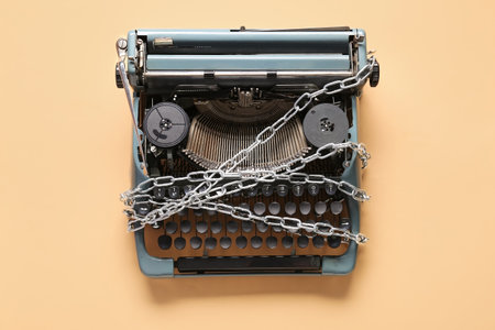 Vintage typewriter with chains on beige background. Printing ban conceptの写真素材