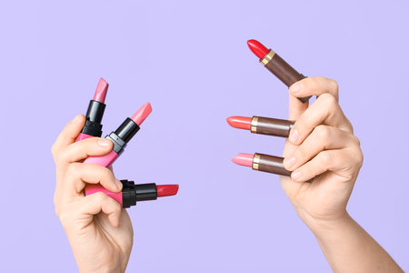 Woman's hands with different lipsticks on lilac backgroundの写真素材