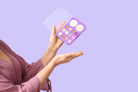 Woman with palette of eyeshadows on lilac backgroundの写真素材