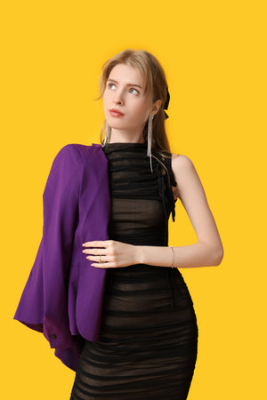 Beautiful young woman with trendy jewelry on yellow backgroundの写真素材