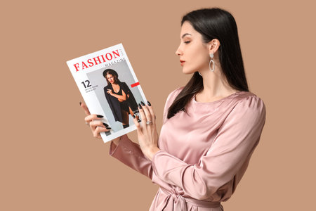 Beautiful young woman with stylish jewelry and magazine on brown backgroundの写真素材